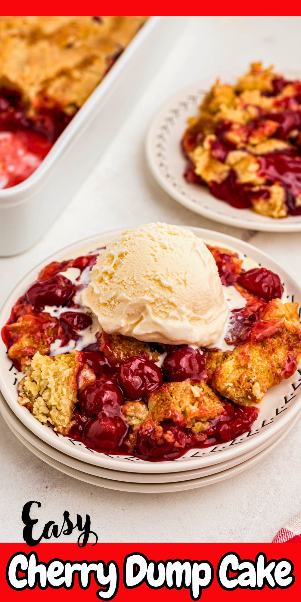 Bright red cherries in a cherry dump cake on a small white plate topped with vanilla ice cream.