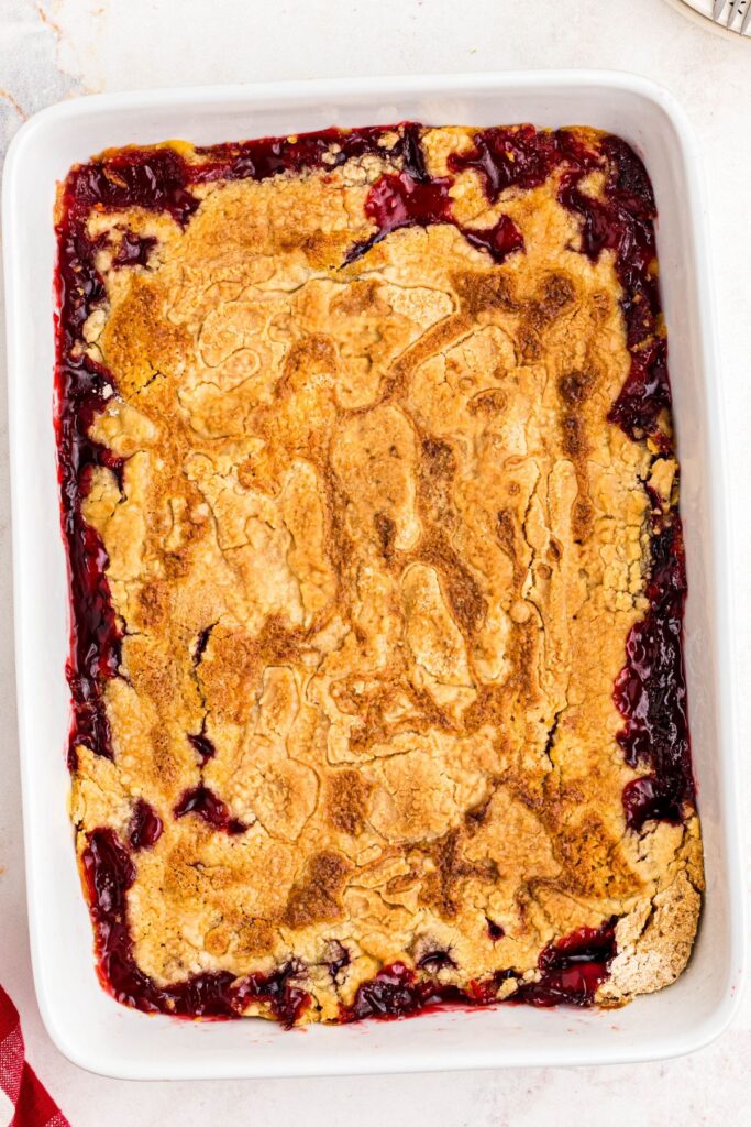 Golden crusted cherry dump cake on a marble table after being baked in the oven. 