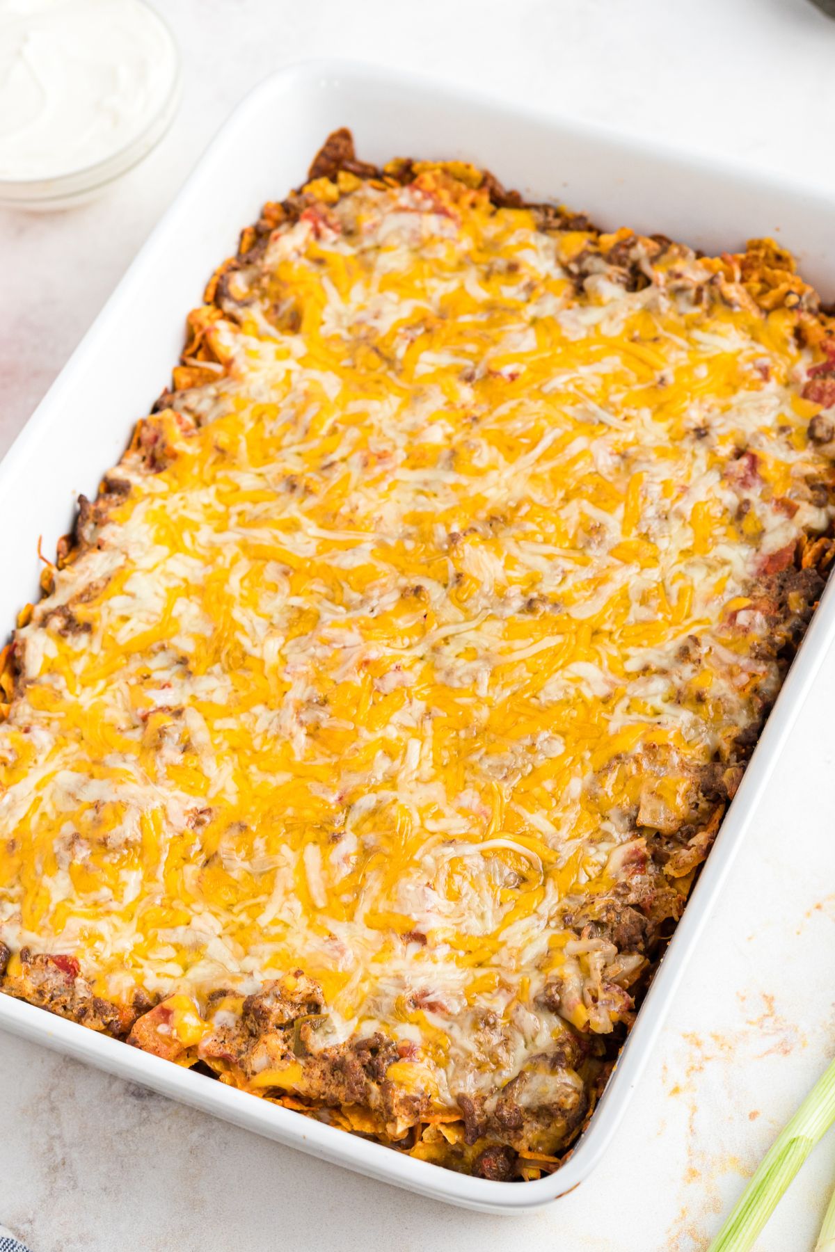 Meat, Doritos, and melted cheese on top in a white casserole dish.