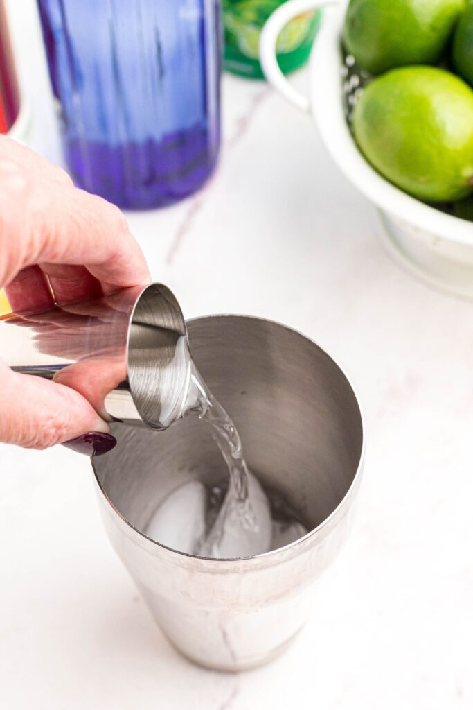 Vodka measured out and poured into a cocktail shaker with ice. 