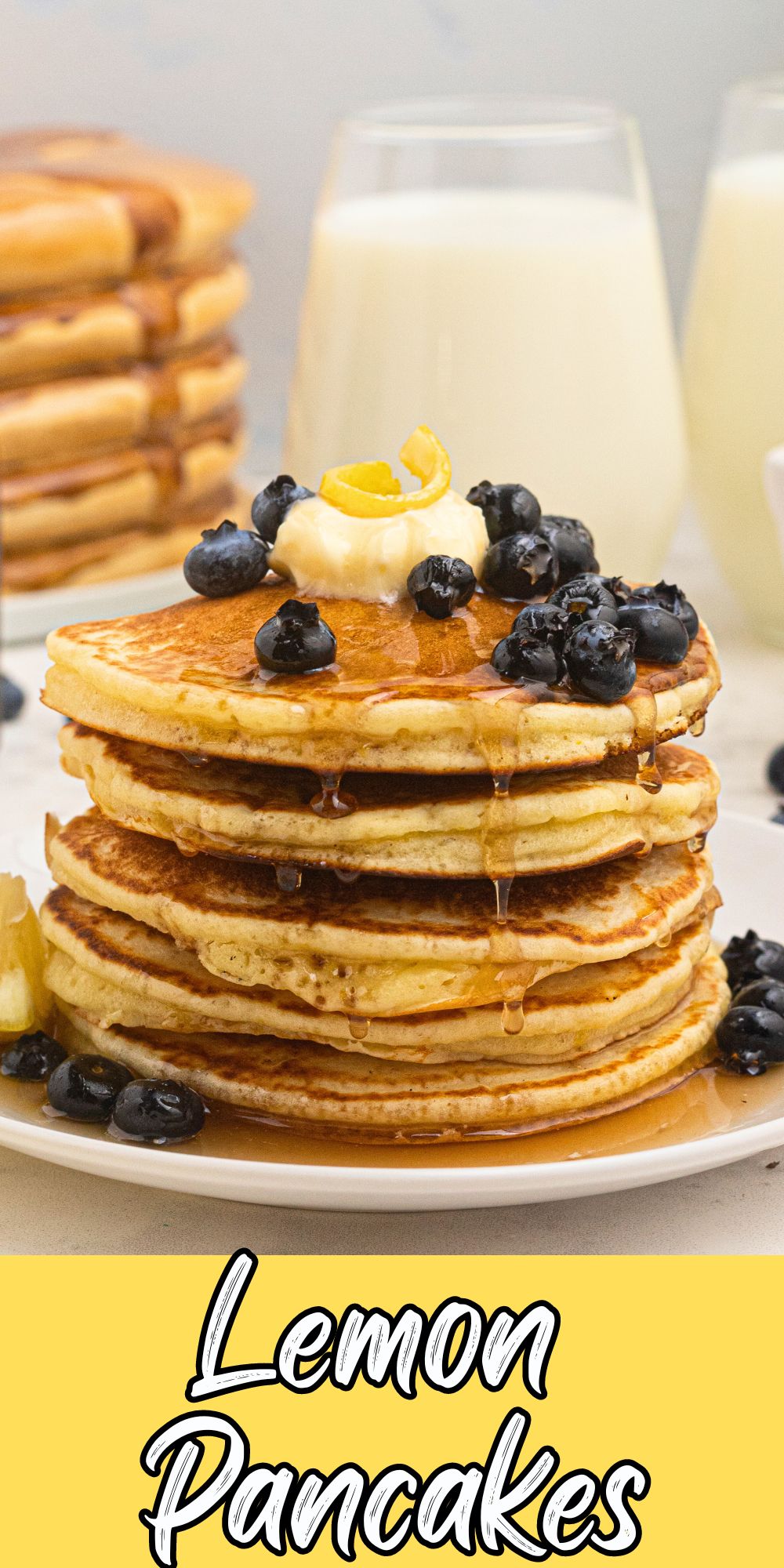 Golden light and fluffy pancakes, stacked on a plate with butter and syrup on top.