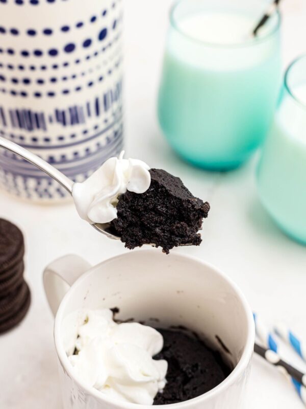 Moist chocolate piece of cake scooped up on a fork with a small dollop of cool whip.