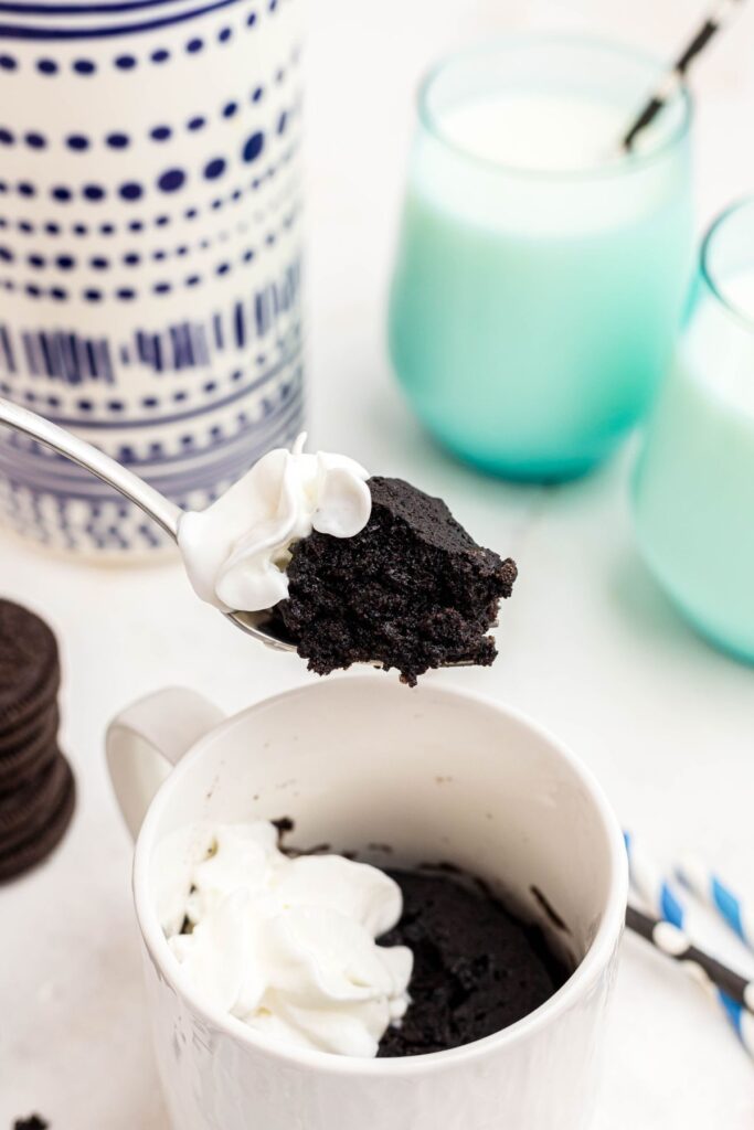 Moist chocolate piece of cake scooped up on a fork with a small dollop of cool whip.