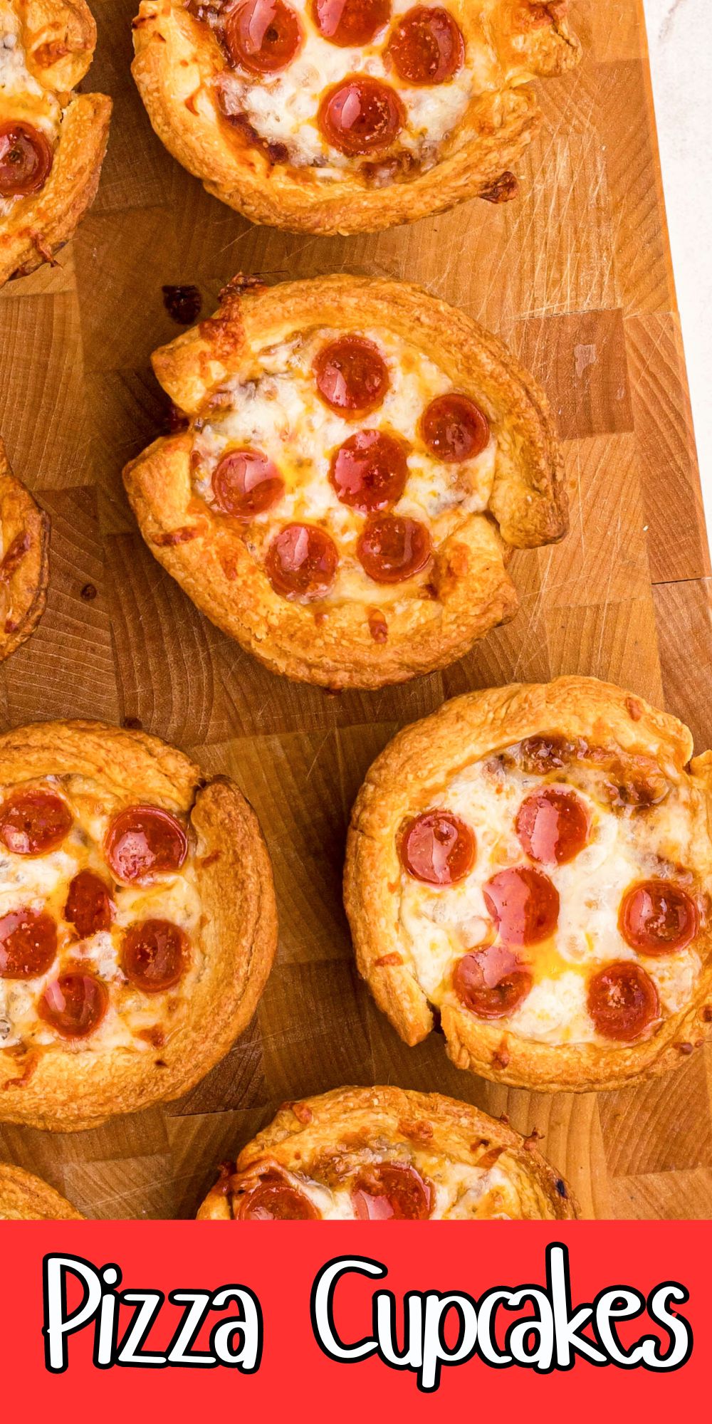 Golden brown baked pizza cupcakes on a wooden cutting board.