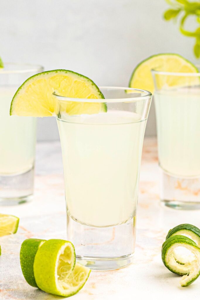 Kamikaze shots on a marble table with lime wedges. 