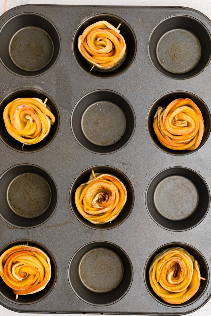 Rolled ap0ple roses in a muffin pan before being baked. 