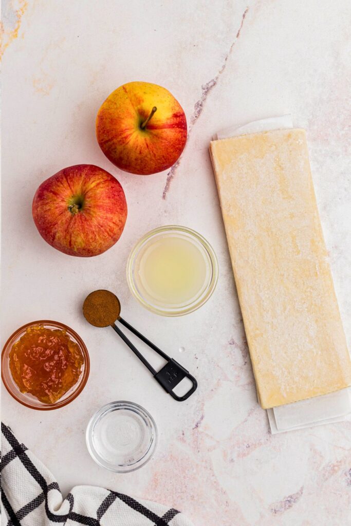 Ingredients needed to bake apple roses, measured on a marble table. 