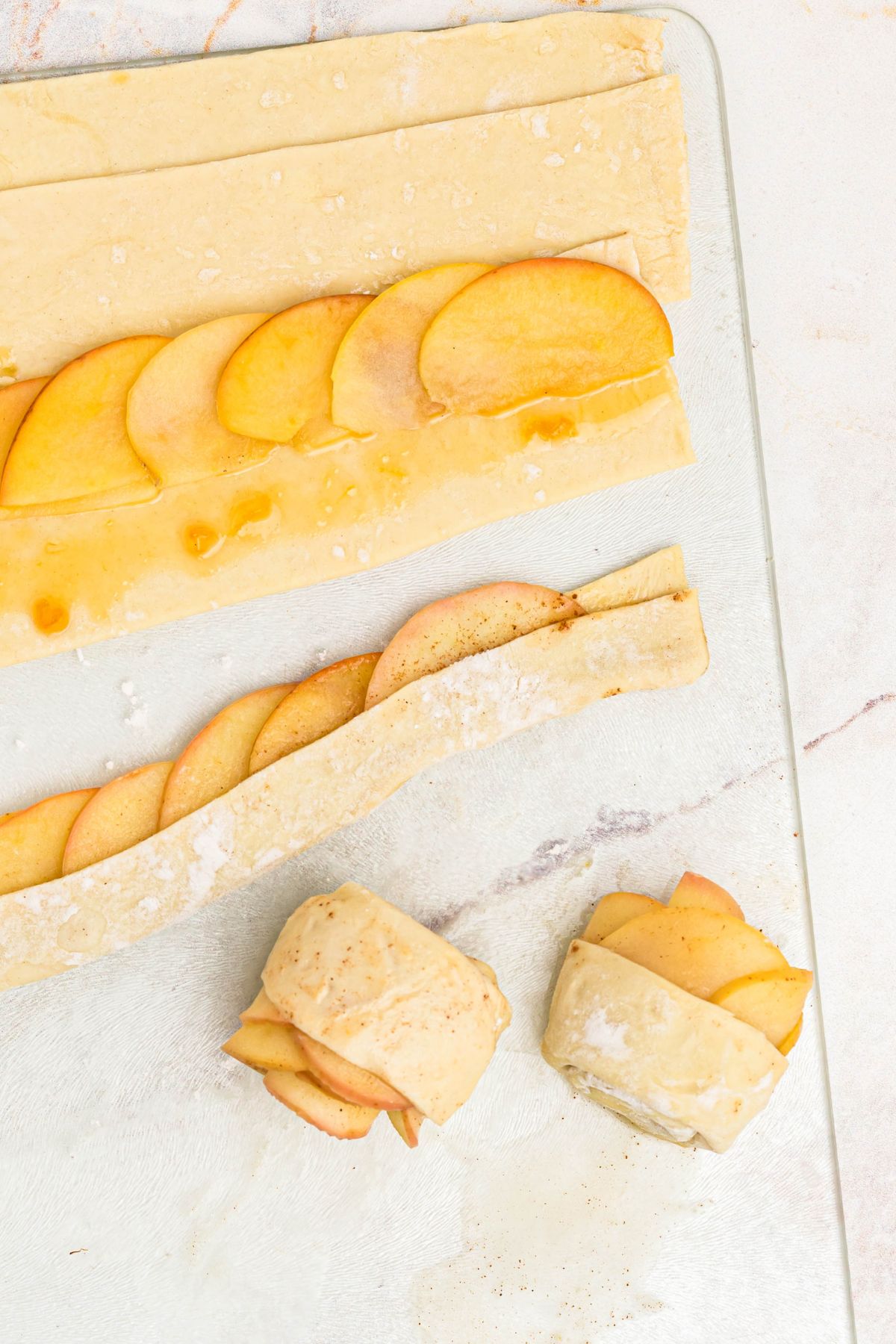 Puff pastry cut into strips with softened apples lining across the strip and then being rolled into roses.