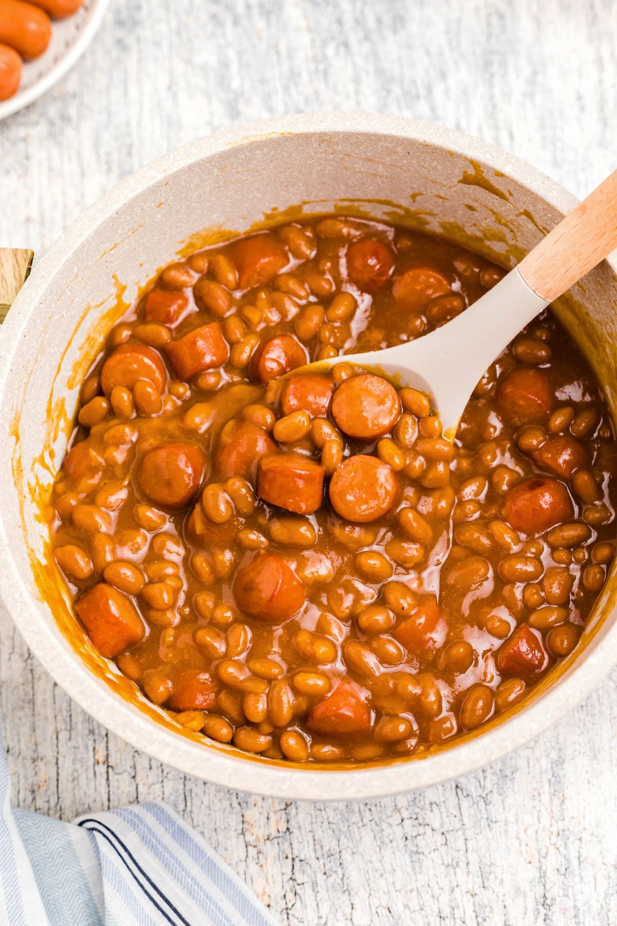 Juicy Beanie weenies being scooped up out of a large saucepan.