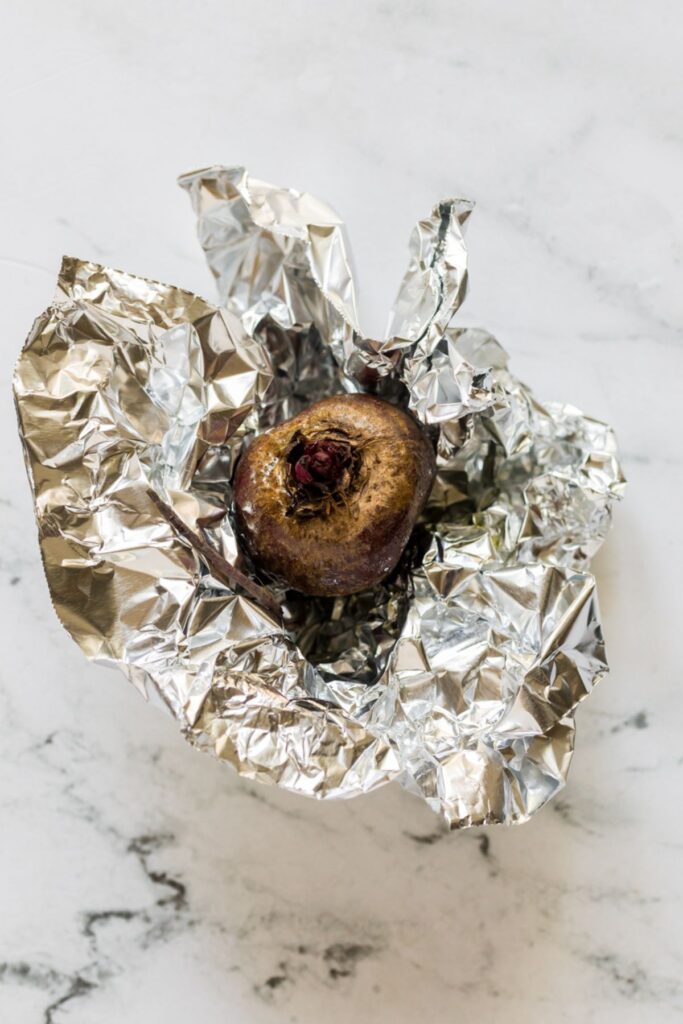 Roasted beet wrapped in foil on a marble table. 