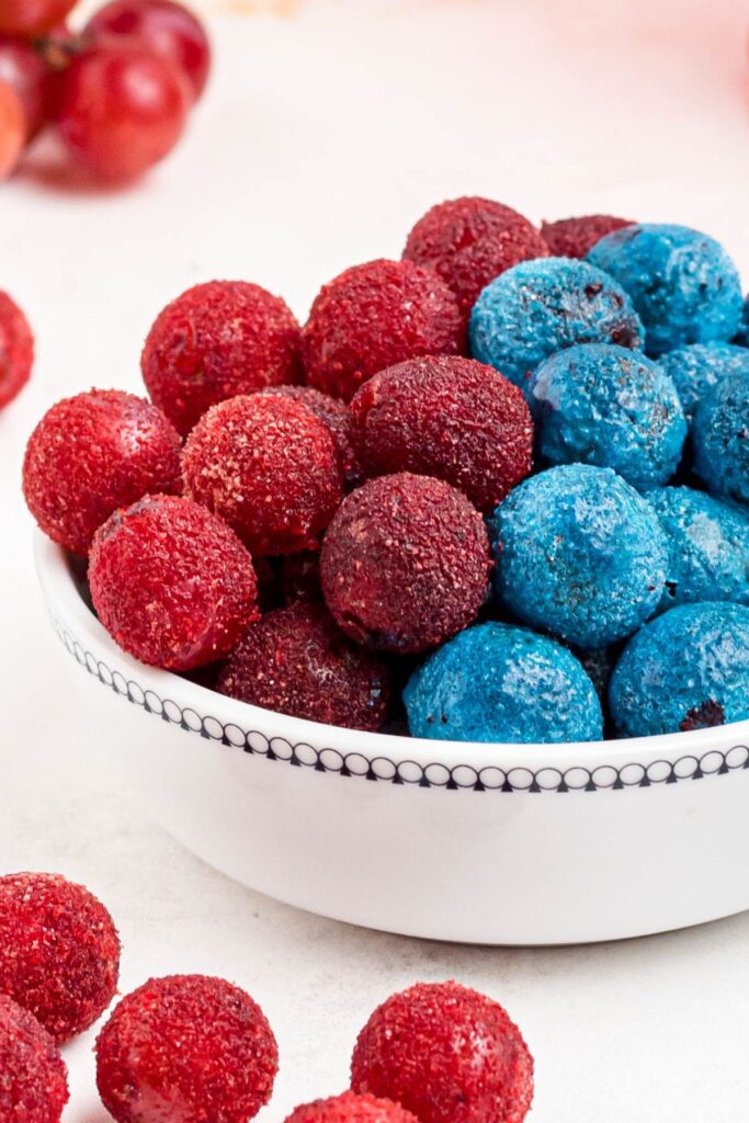 Red powder coated grapes in a white bowl. 