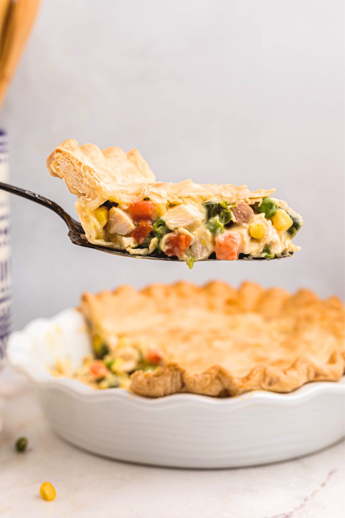 Creamy chicken pot pie in a flaky pie crust being served with a spatula. 