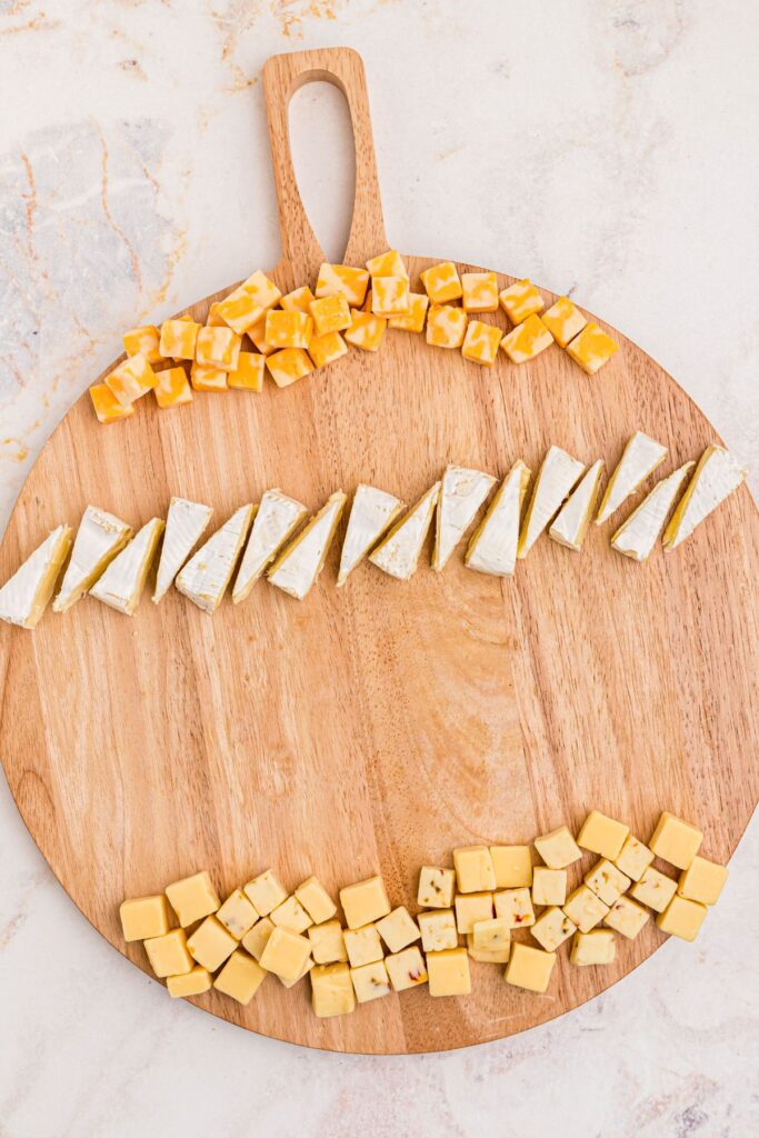 Cheeses spread out on a charcuterie board.