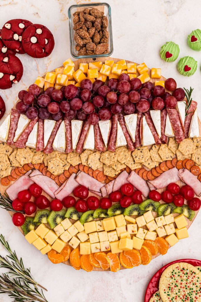 Full charcuterie board with fruits, meats, and cheeses, with treats on the table. 