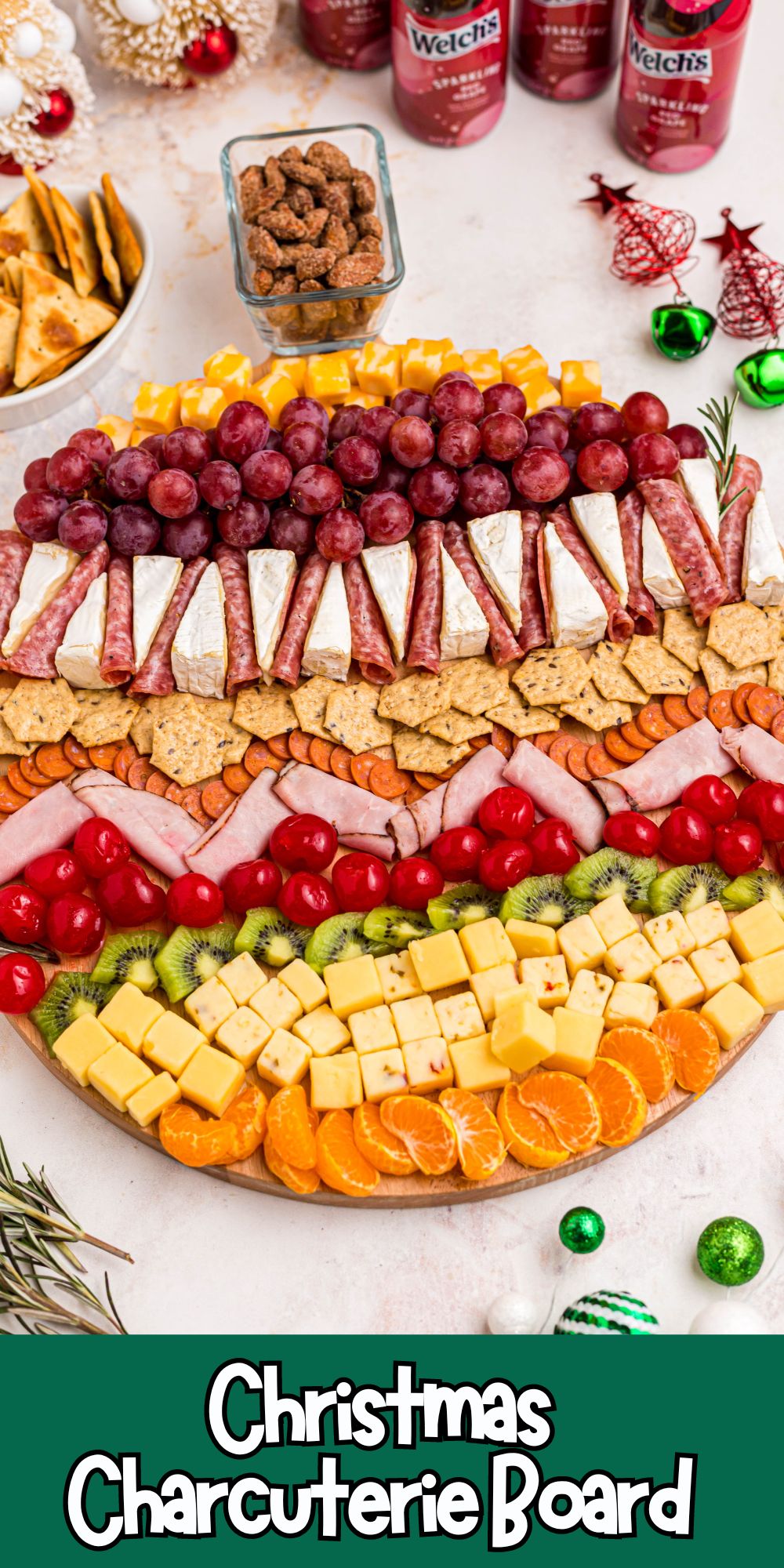 Meats, cheeses, fruits, crackers, and nuts on a Christmas charcuterie board.