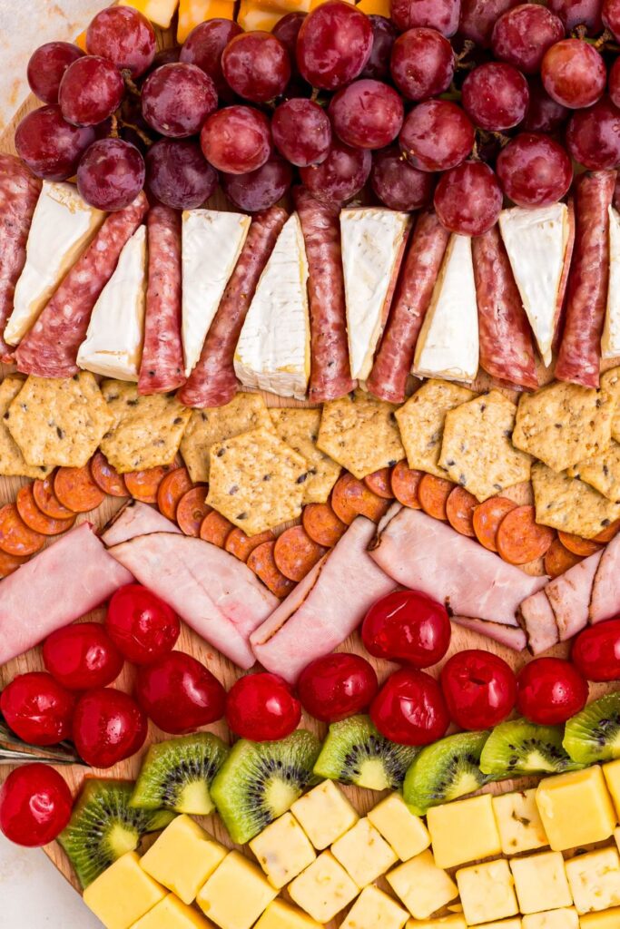 Fun and colorful fruits, meats, and cheeses on a charcuterie board. 