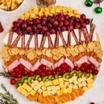 Meats, cheeses, and fruits on a board in the shape of an ornament.