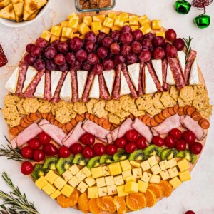 Meats, cheeses, and fruits on a board in the shape of an ornament.