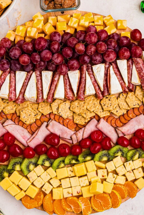 Meats, cheeses, and fruits on a board in the shape of an ornament.