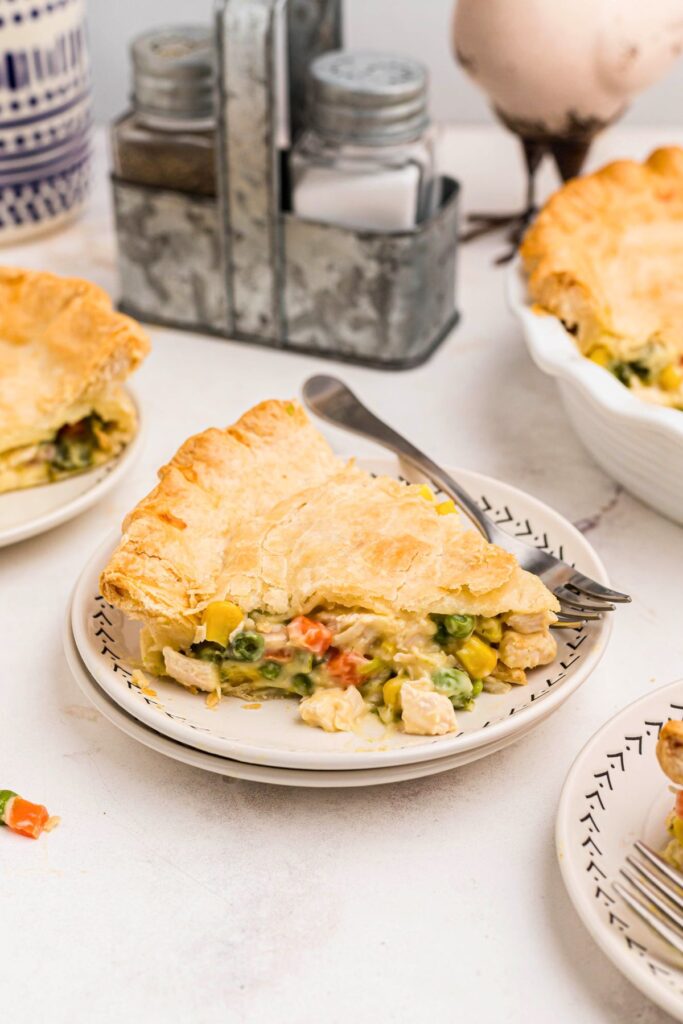 Golden crusted chicken pot pie filled with chicken and veggies on a white plate.