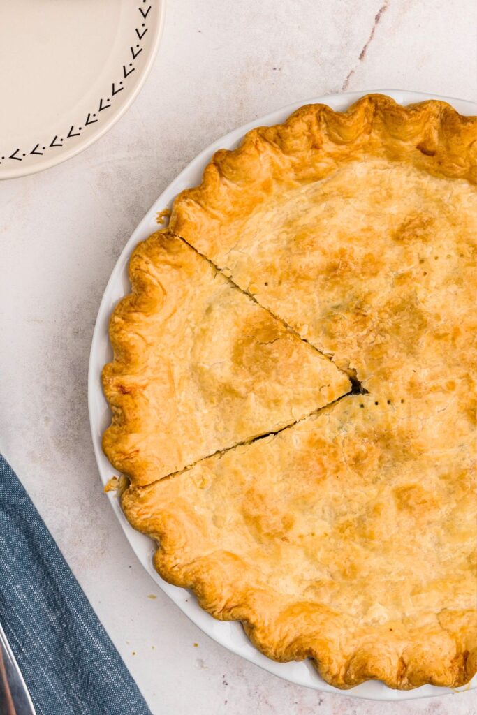 Golden pie in a white pie plate with a piece cut. 