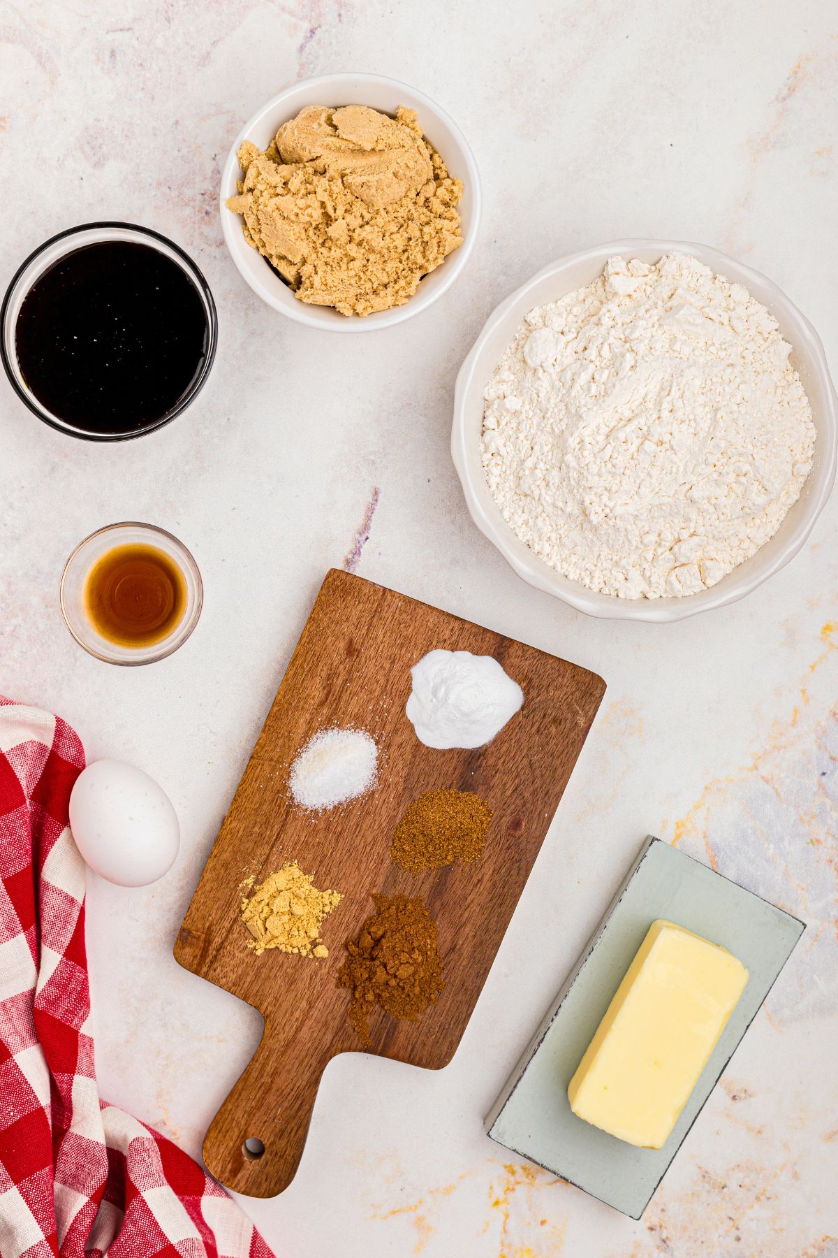 Ingredients needed to make gingerbread cookies measured in small dishes, on a marble table. 