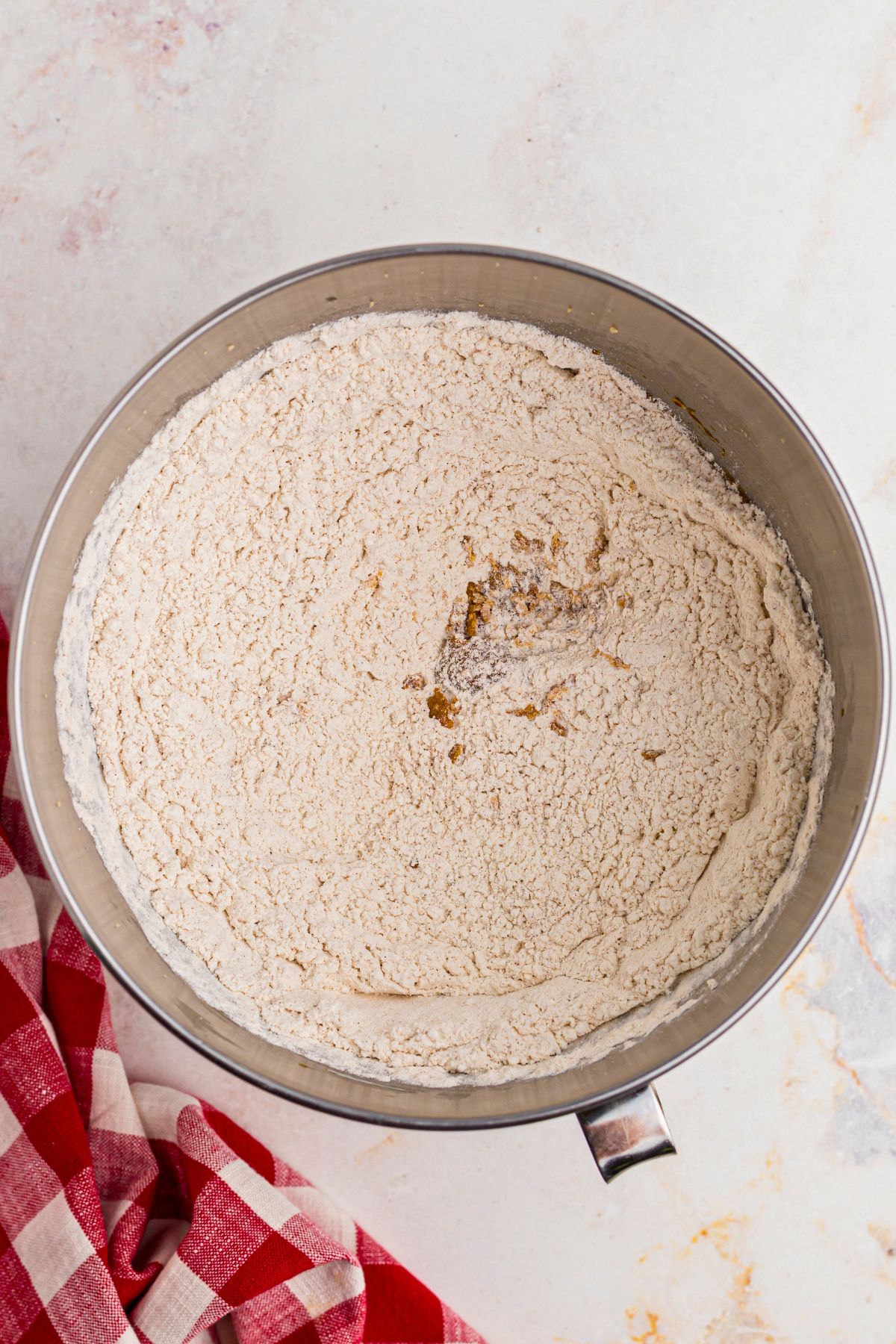 Flour and other dry ingredients mixed together in a silver mixing bowl. 