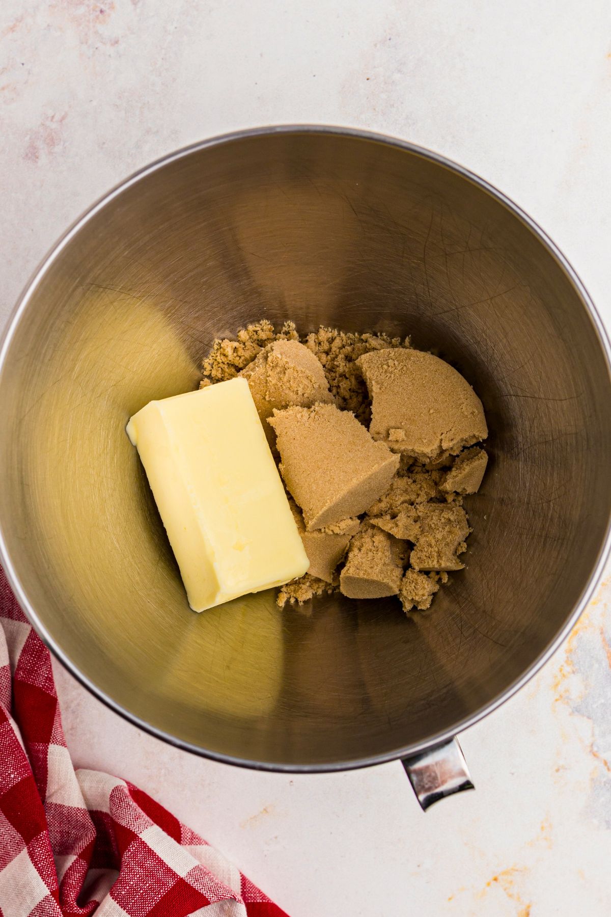 Butter and brown sugar in a silver mixing bowl before mixing together. 