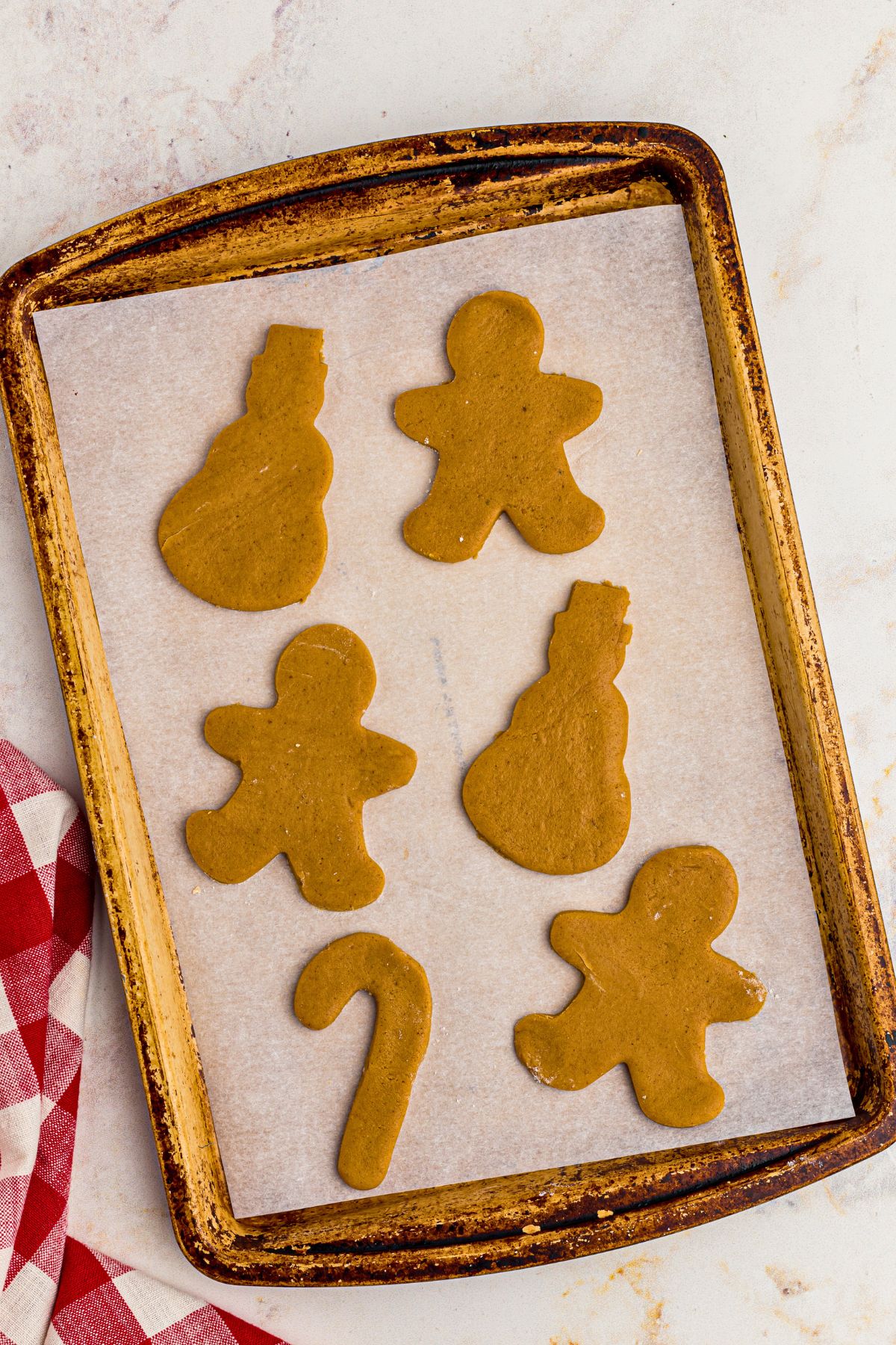 Uncooked gingerbread cookies on a baking sheet lined with parchment paper. 