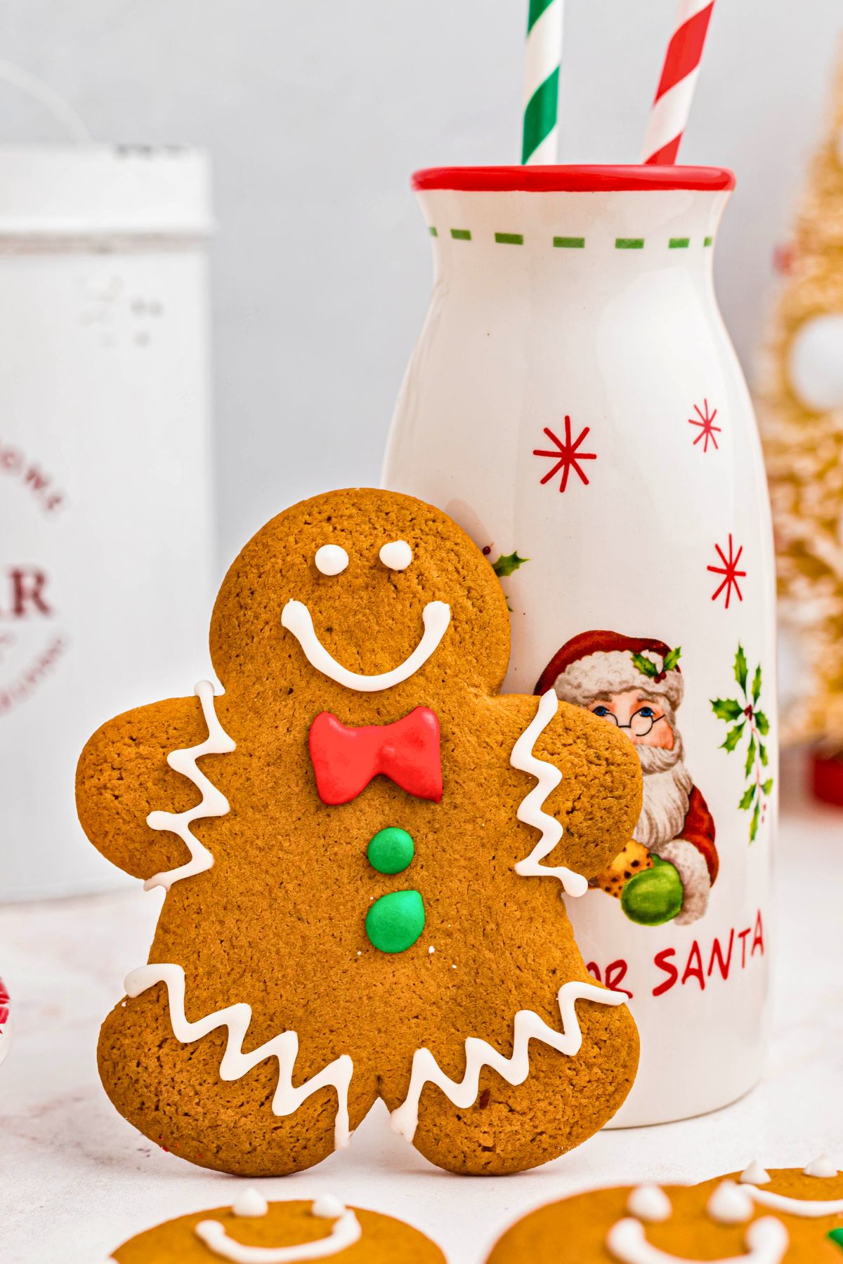 Gingerbread man cookie leaning up against a bottle of milk. 