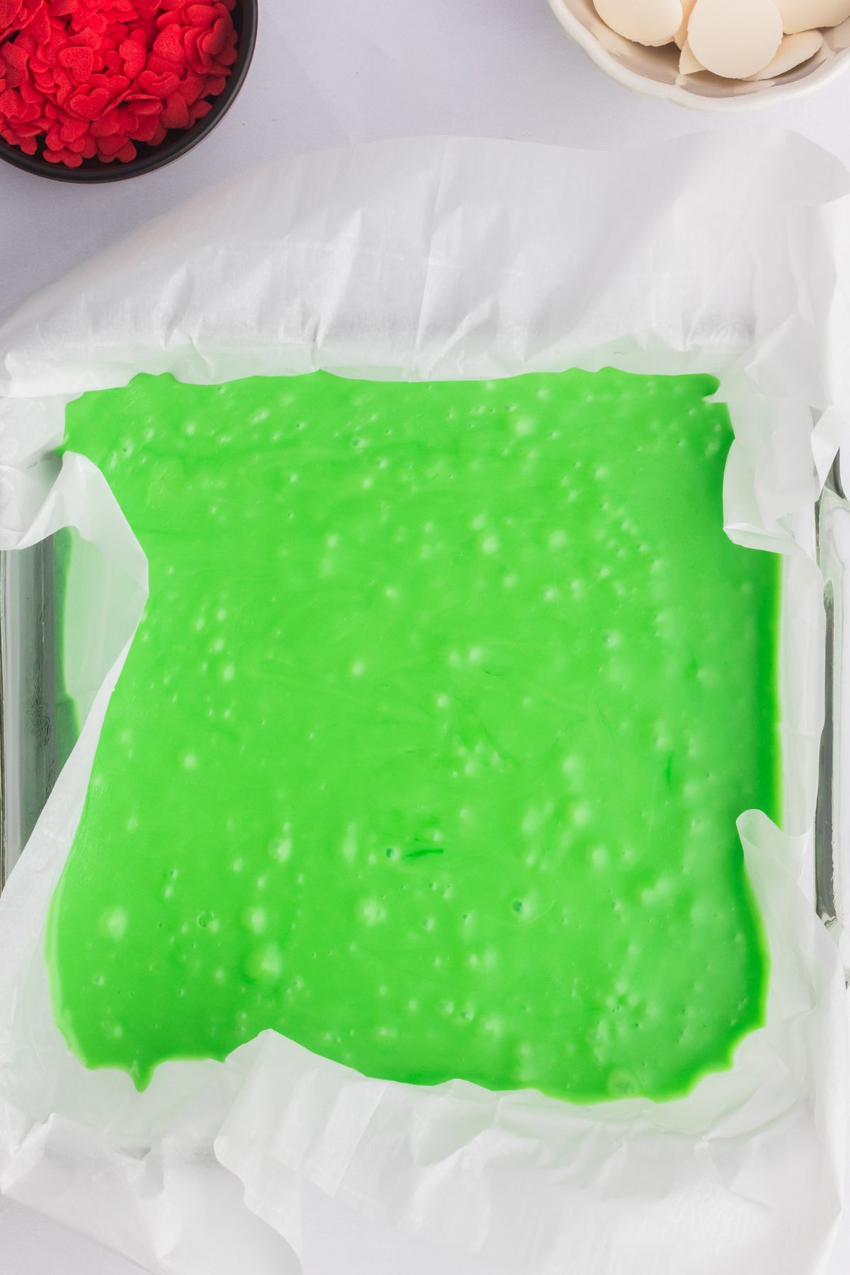 Bright green Grinch fudge in a square baking pan, waiting to set. 