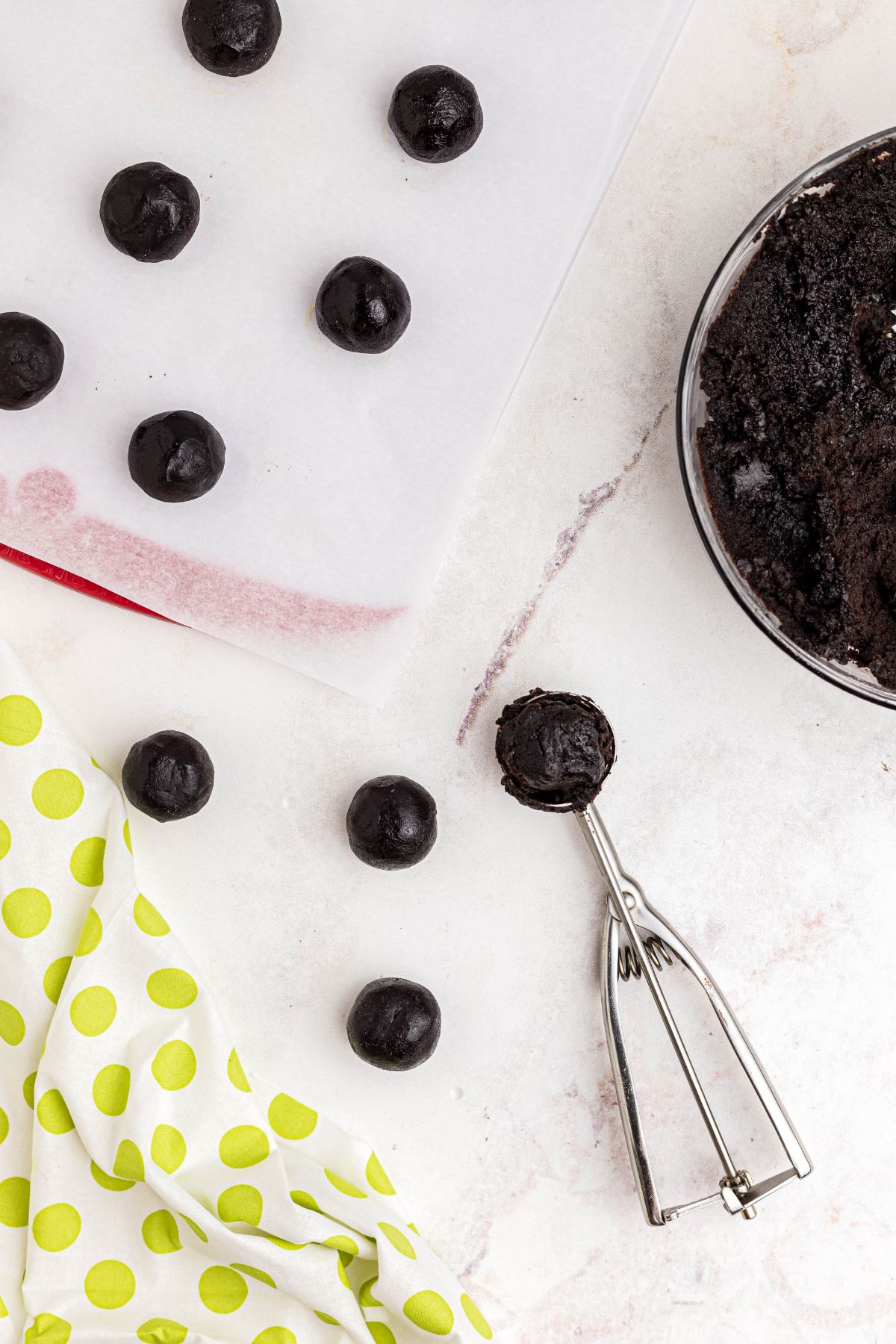 Cookie scoop shaping Oreo and cream cheese mixture into ball shapes.