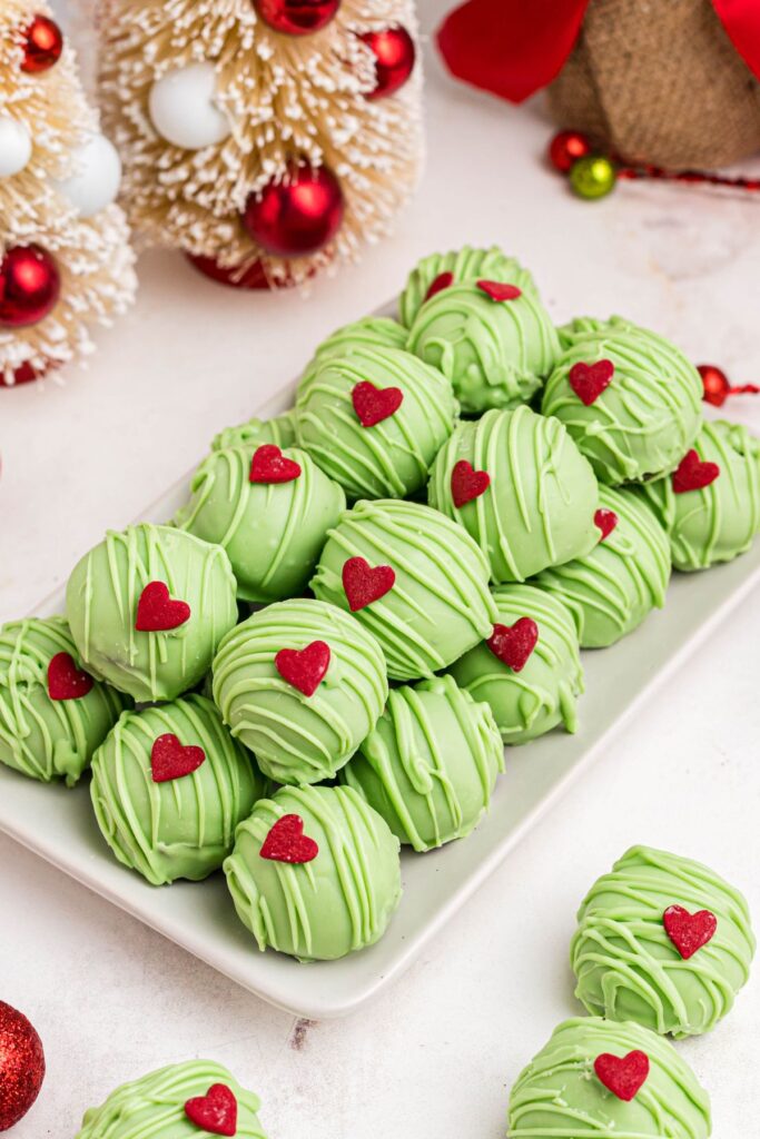 Green Grinch Oreo balls stacked on a white plate. 