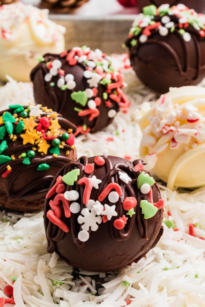 Milk chocolate cocoa bombs with holiday sprinkles on a table. 