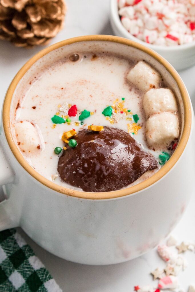 Cocoa bomb in a mug of hot milk with sprinkles and mini marshmallows.