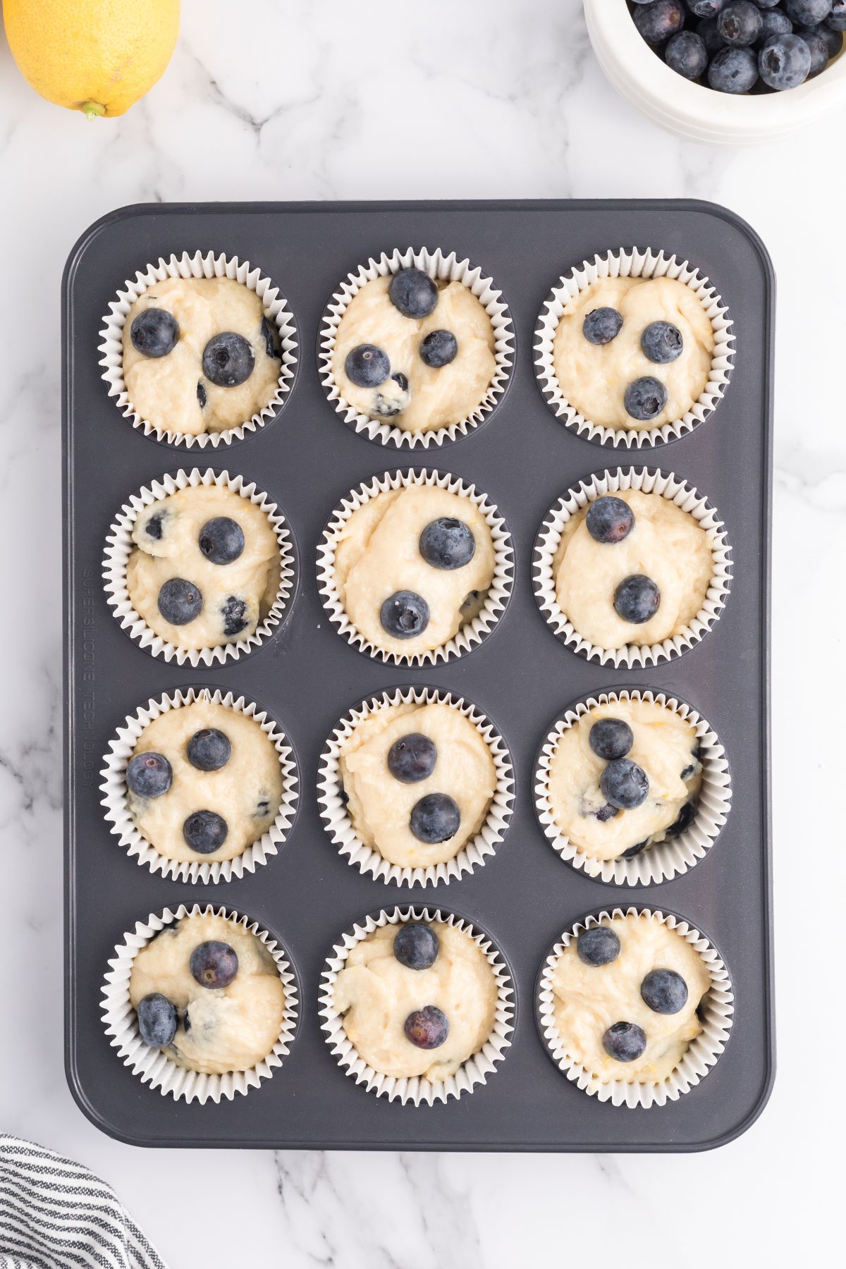 Uncooked blueberry muffins in a lined muffin pan.