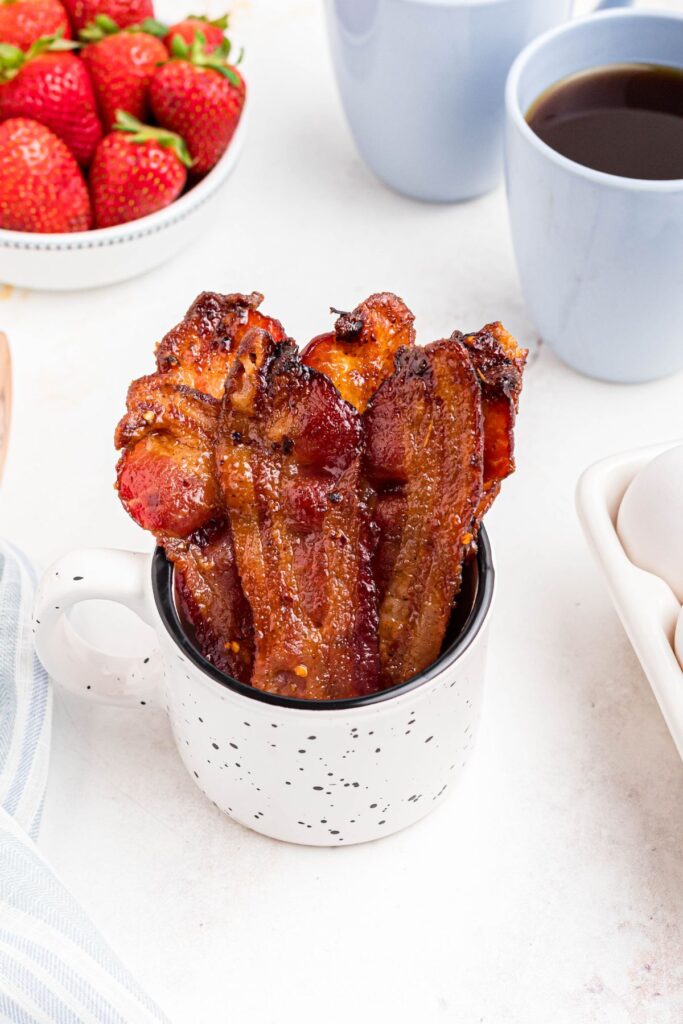 Golden bacon in a mug in front of coffee and berries. 