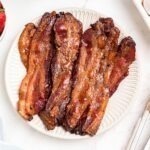 Golden bacon slices on a white plate.