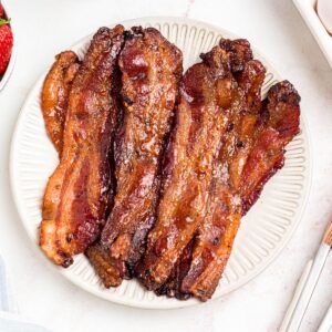 Golden bacon slices on a white plate.