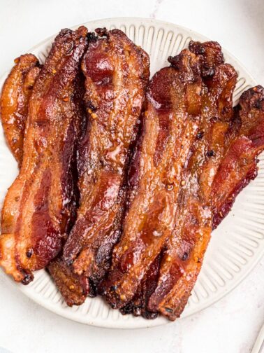 Golden bacon slices on a white plate.