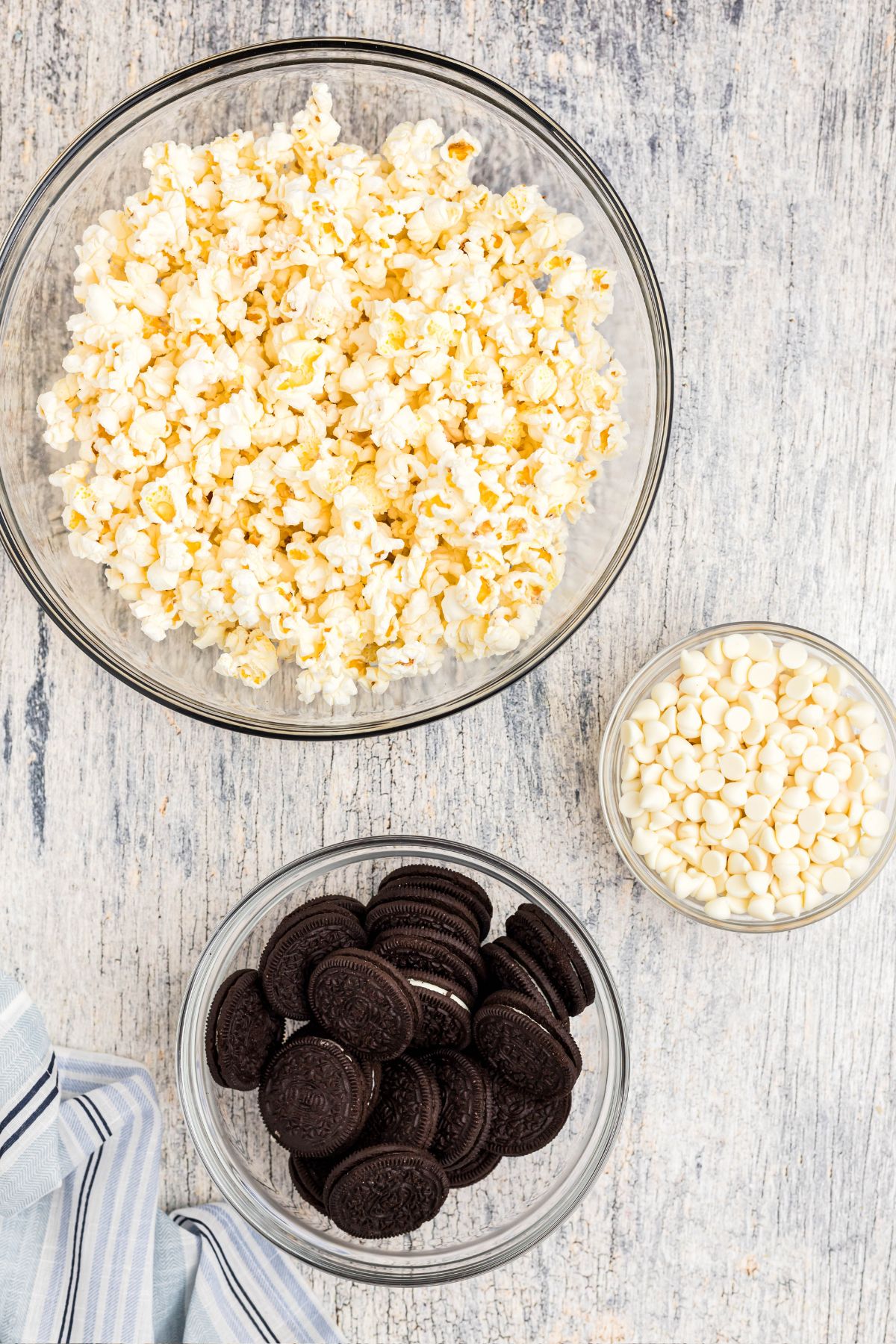 Ingredients needed to make Oreo popcorn measured into clear glass bowls. 