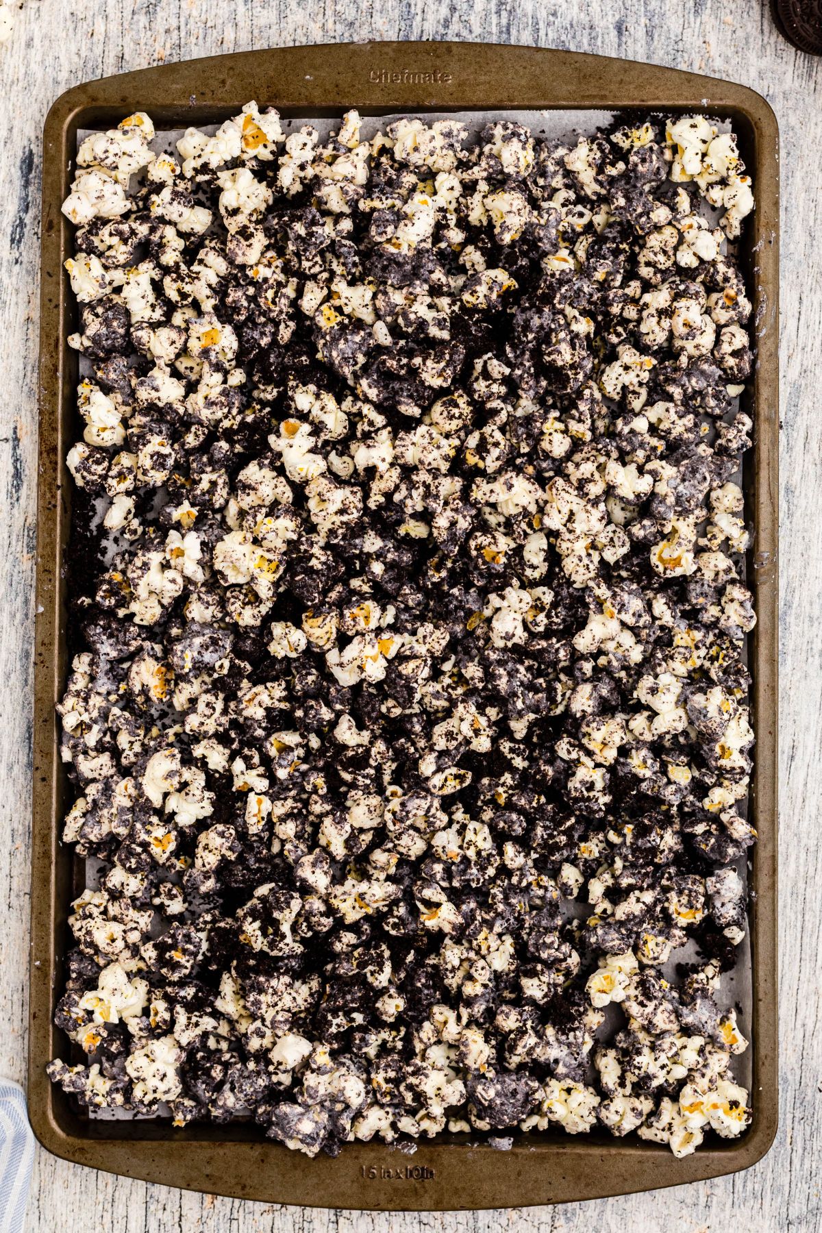 White chocolate mixed with crushed Oreos and popcorn, spread out on a baking sheet lined with parchment paper. 