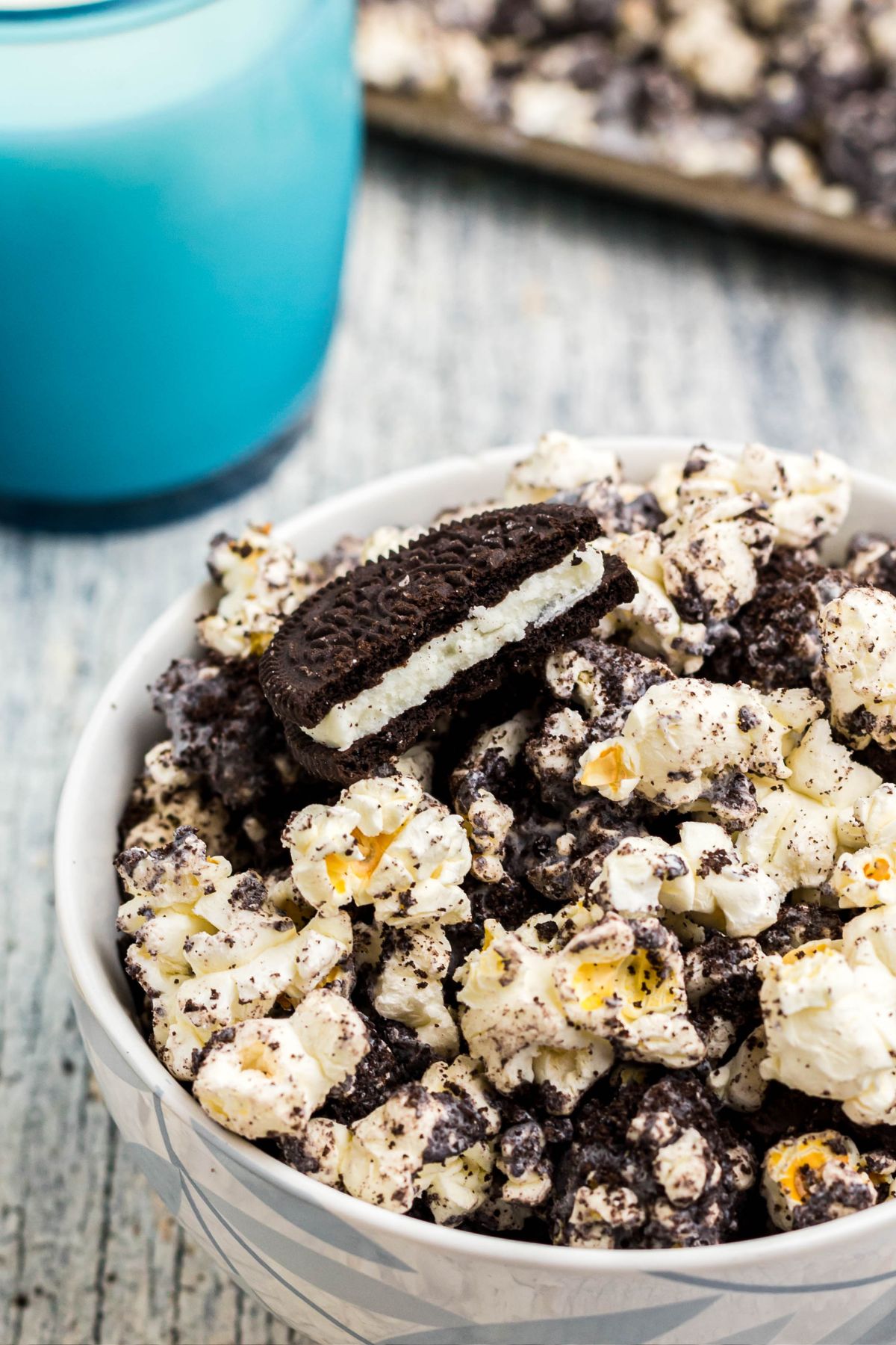 Close up photo of an Oreo cookie broken in a bowl of popcorn. 