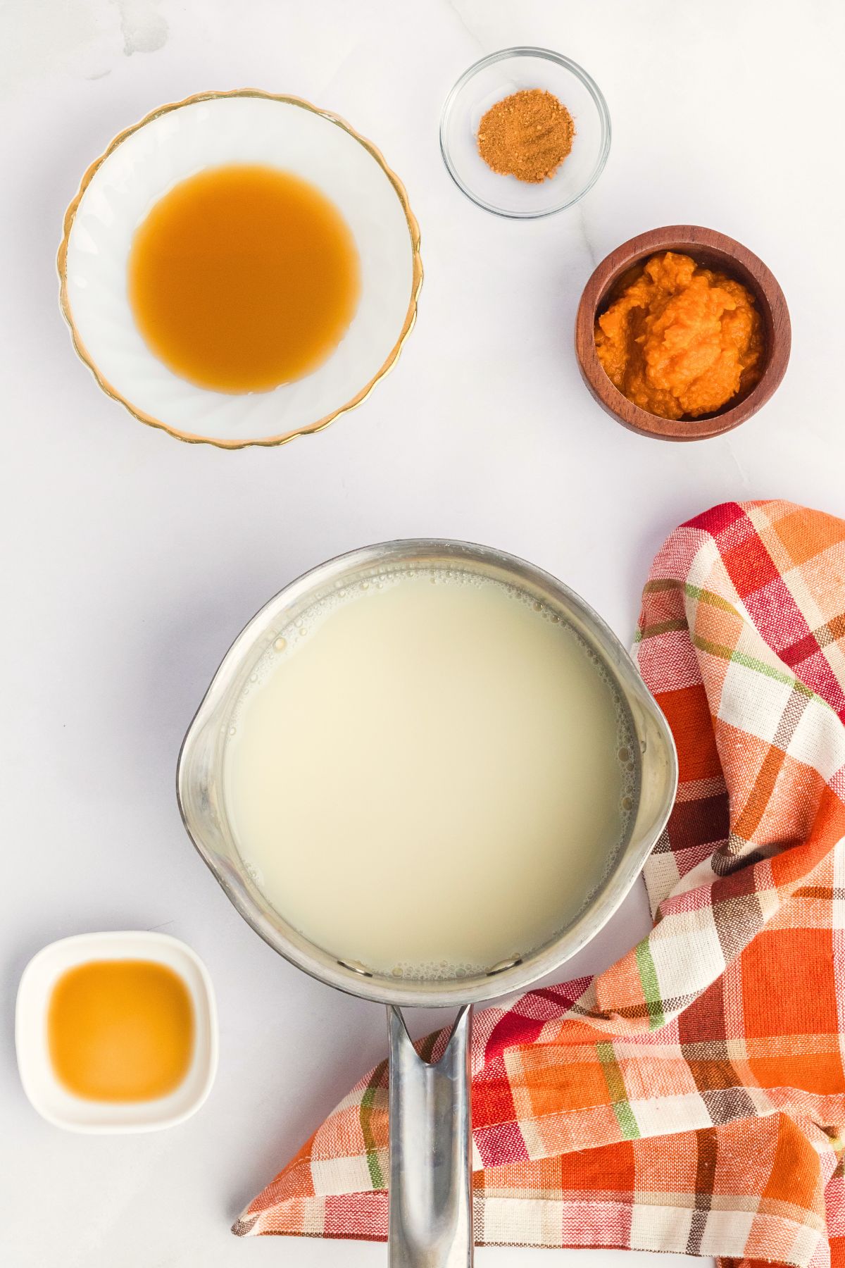 Ingredients needed to make creamer measured into small bowls on a white marble table. 