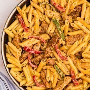 Juicy pasta noodles with bell peppers and chicken along with a creamy sauce in a large skillet.