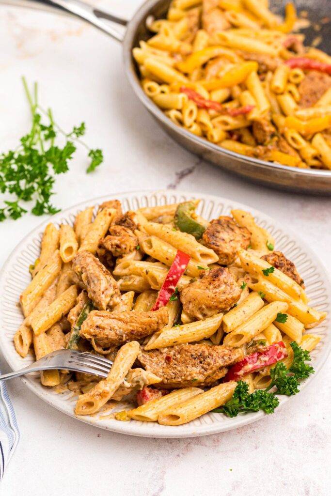 Chicken and pasta on a white plate with cream sauce. 