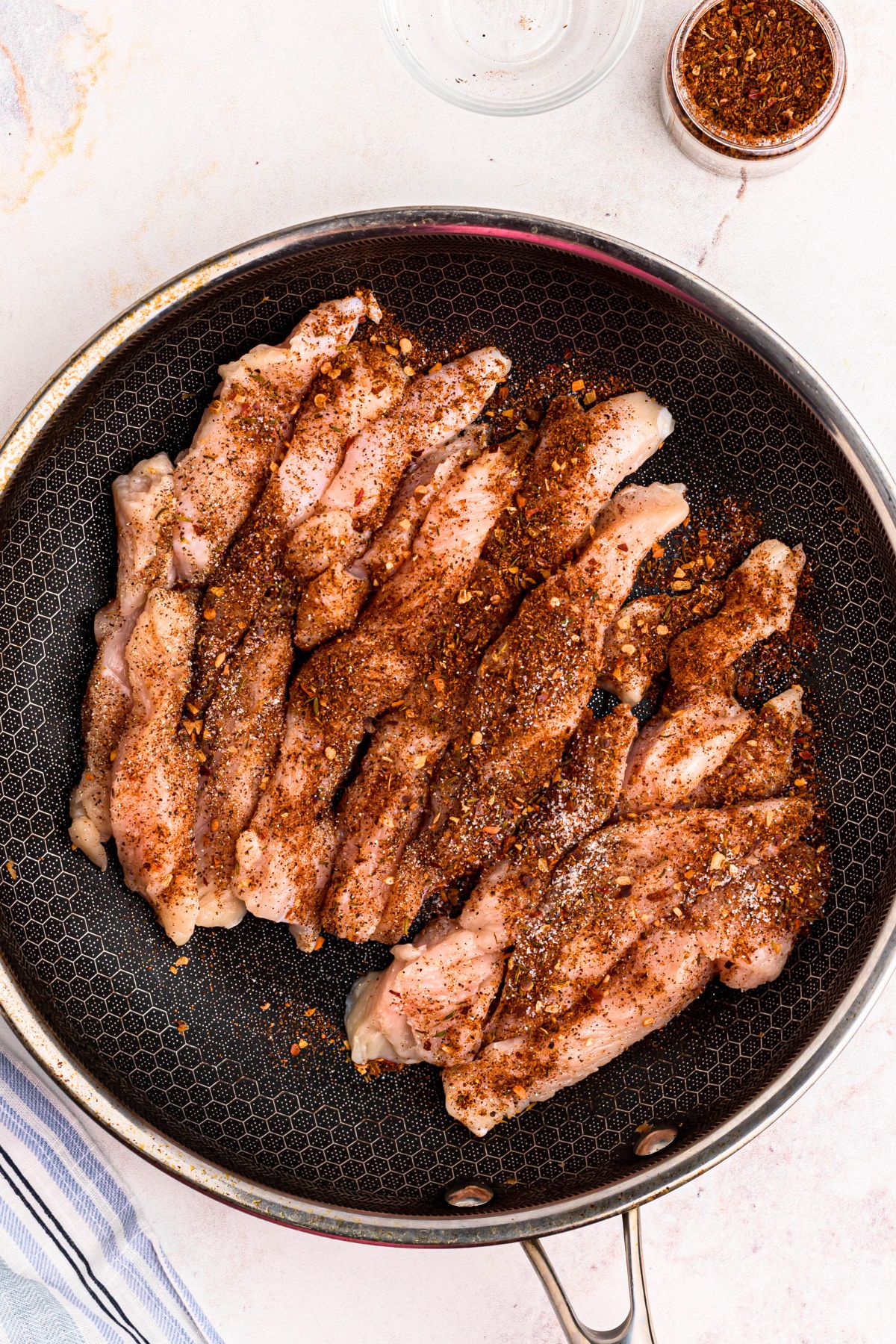Seasoned uncooked chicken in a large skillet.