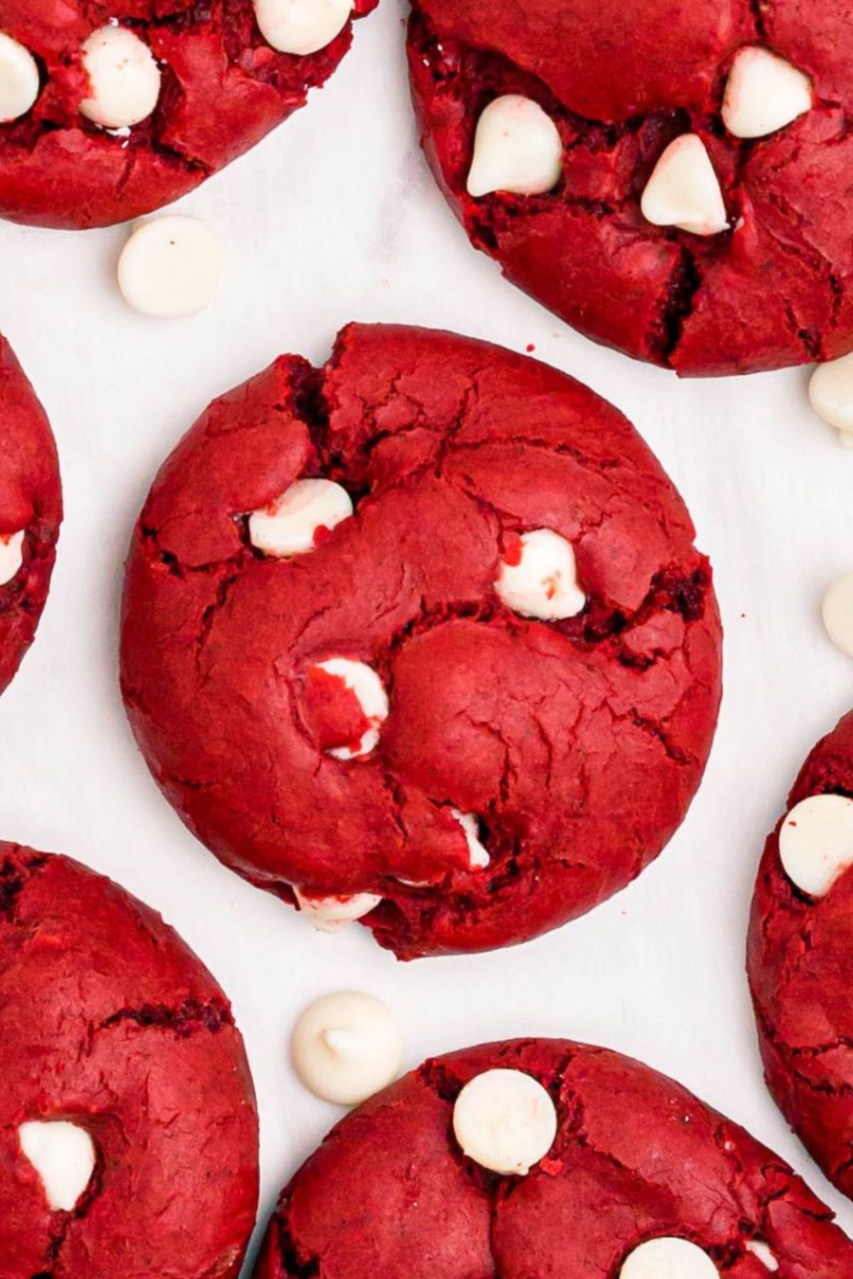 Red cookies with white chocolate chips in them on a marble table.