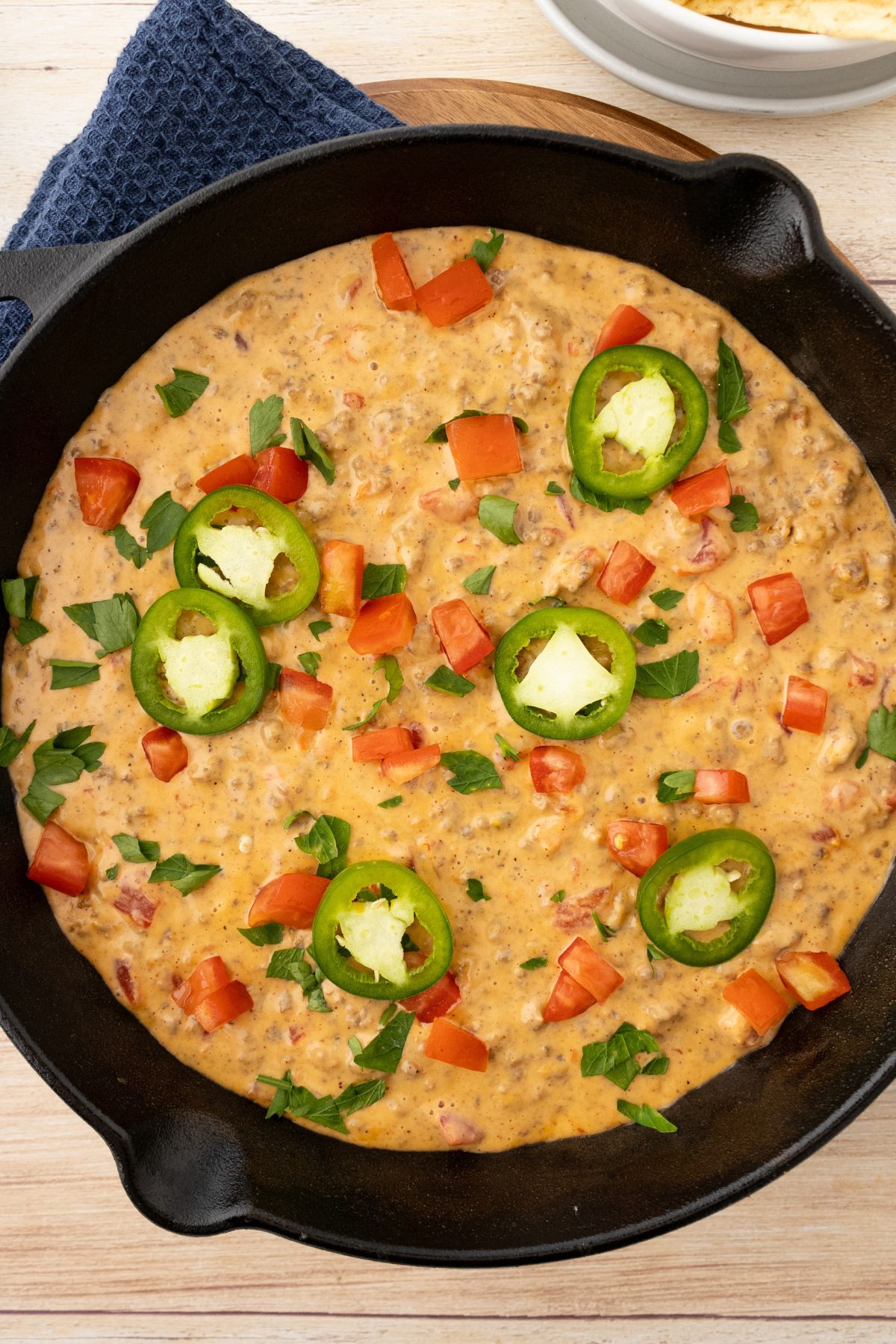 Rotel dip in a black skillet topped with jalapenos and diced tomatoes.