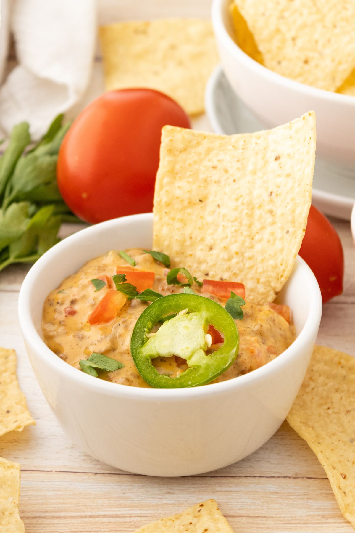 Rotel dip in a small white bowl with tortilla chip dipped off to the side. 